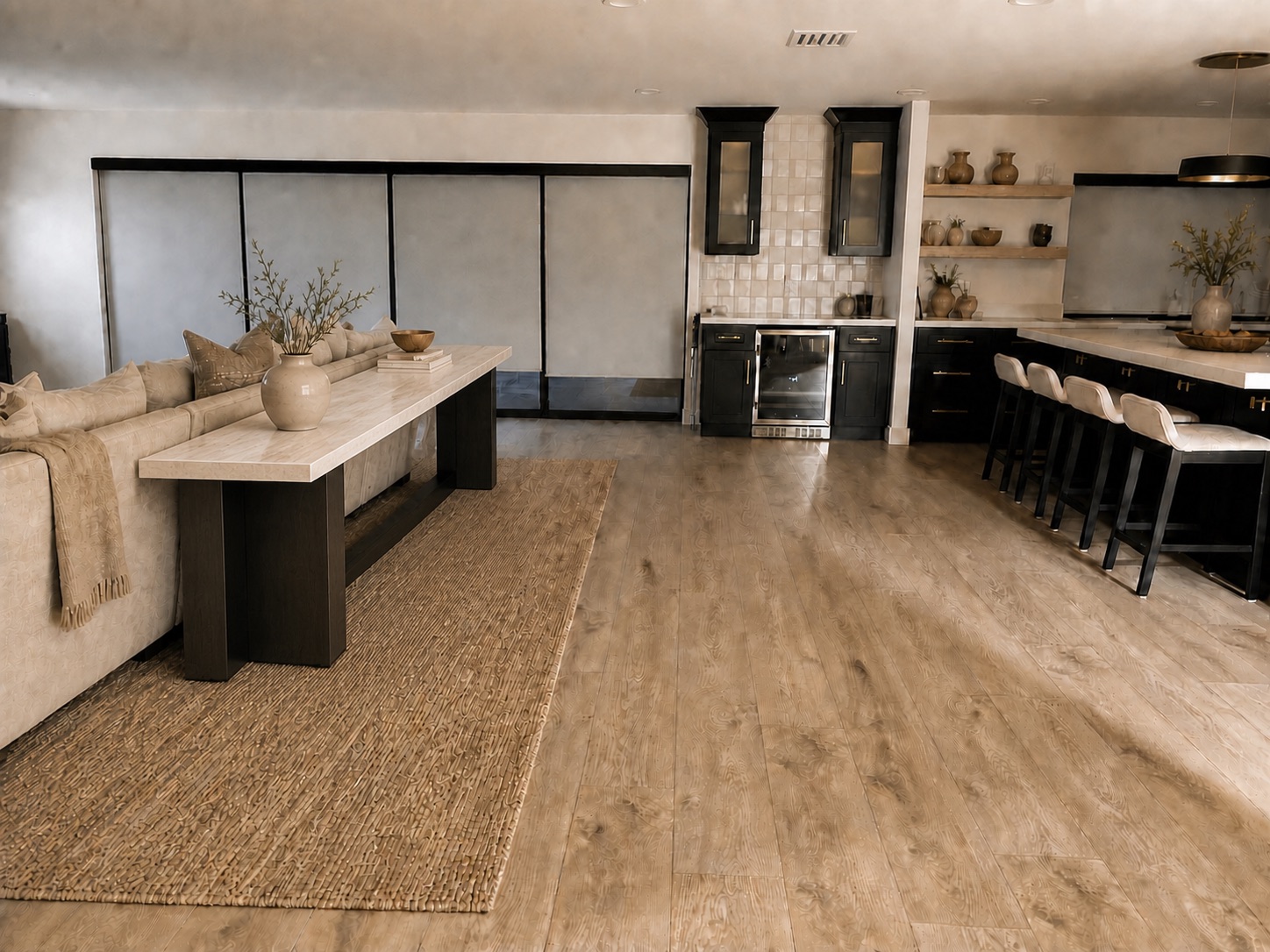 Professionally staged Valle de Luna living room with a long luxury stone and dark wood sofa table, bar, and kitchen